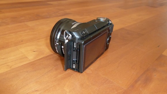 Sony NEX-3N mit offenem Seitenfach für USB-Anschluss und Speicherkarte.